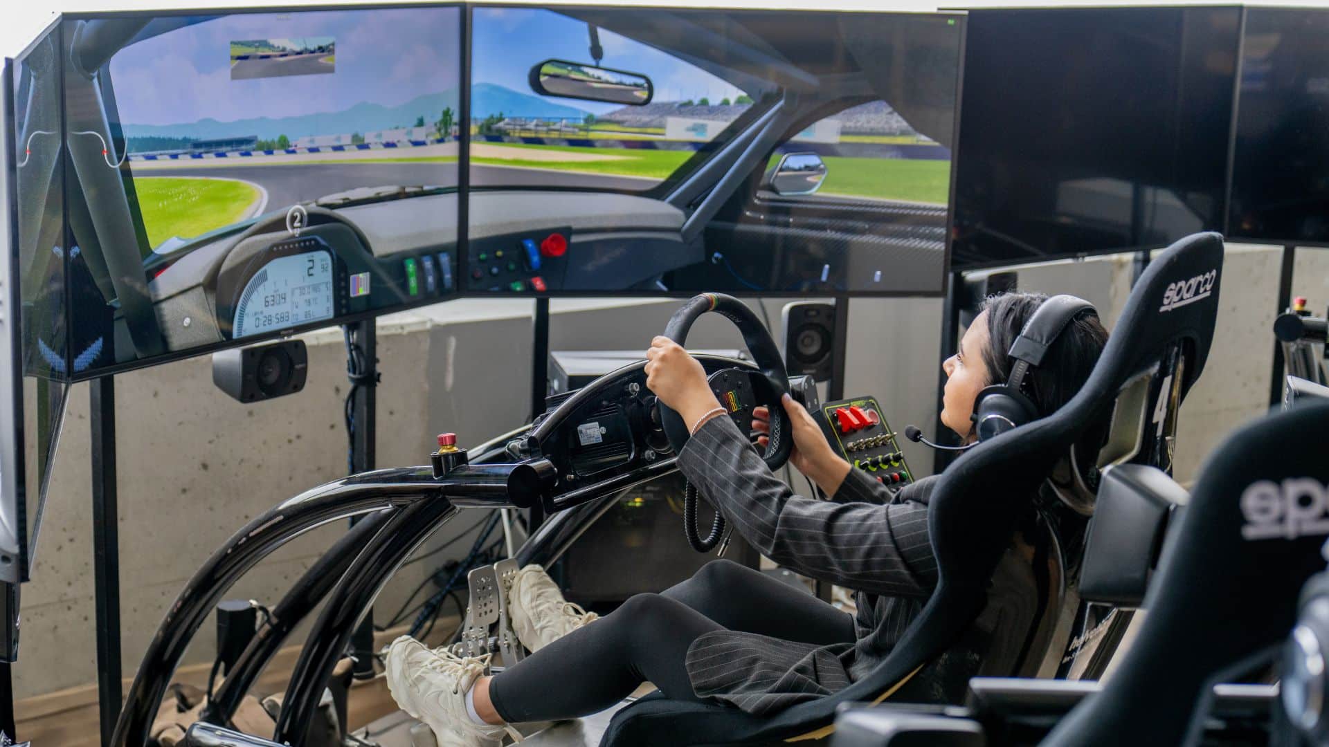 Eine Frau sitzt am Rennsimulator in der Jochen Schweizer Arena und spielt ein virtuelles Rennspiel